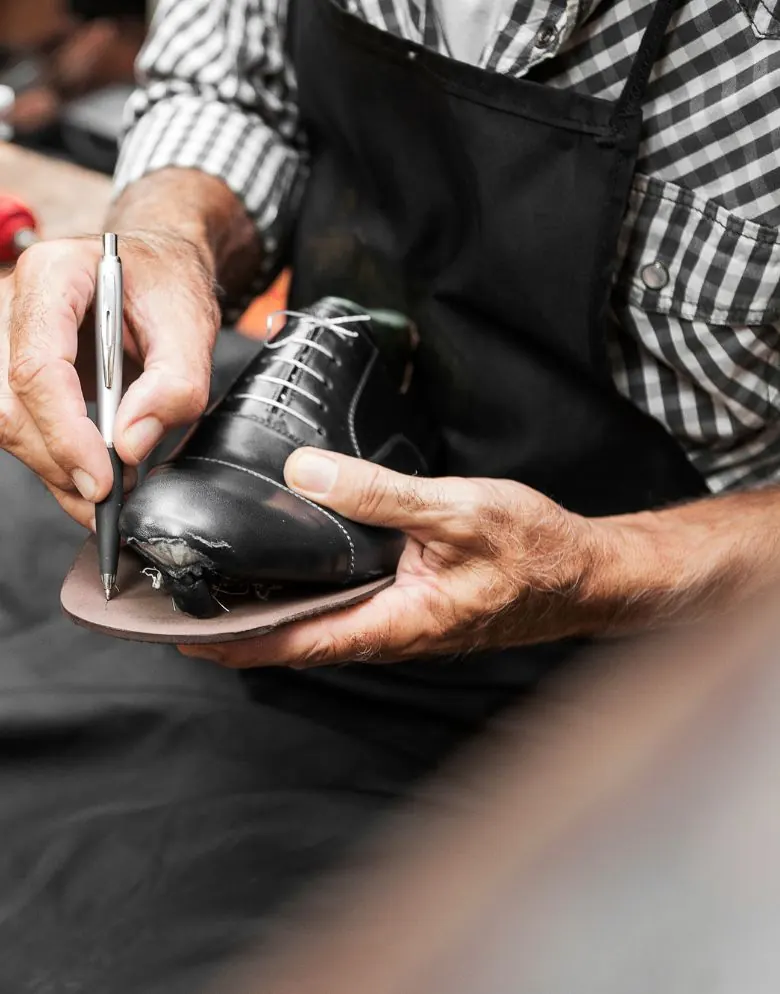 Manos de artesano dando forma a un zapato sobre su suela